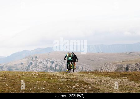 back two cyclists riding on mountain road on mountain bike Stock Photo