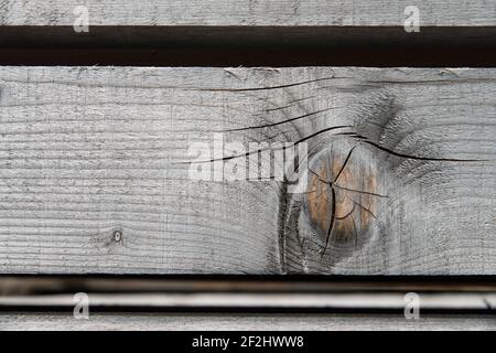 Faded, parallel wooden slats with knotholes and cracks against a black background Stock Photo