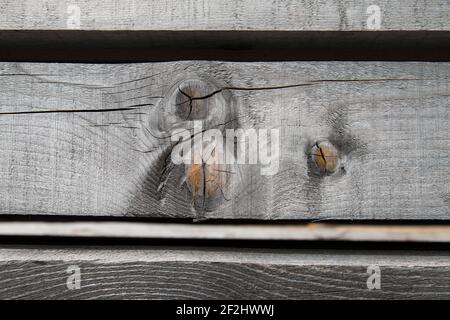 Faded, parallel wooden slats with knotholes and cracks against a black background Stock Photo