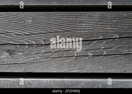 Faded, parallel wooden slats with knotholes and cracks against a black background Stock Photo