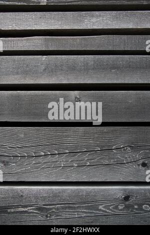 Faded, parallel wooden slats with knotholes and cracks against a black background Stock Photo