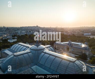 Aerial morning closeup over Grand Palais museum with sun glare/reflection on glass roof and Petit Palais in right backdrop with city view