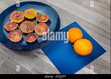 oranges seasoned with oil salt and pepper on a blue plate and wooden background oranges Stock Photo