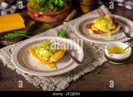Organcic eggs benedict with bacon, cheddar cheese and herbs and hollandaise sauce Stock Photo
