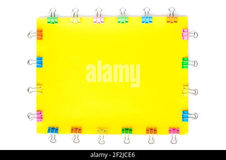 Blank yellow paper sheet with colored small paper clips attached around it, isolated on white background Stock Photo