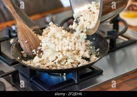 Tofu is filled and fried in a black iron pan on a gas stove Stock Photo