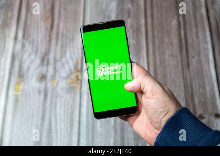 A Mobile phone or cell phone being held in a hand with the BBC Gardeners world app open on screen Stock Photo