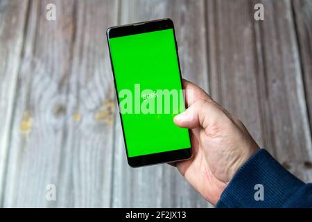 A Mobile phone or cell phone being held in a hand with the Geek app open on screen Stock Photo