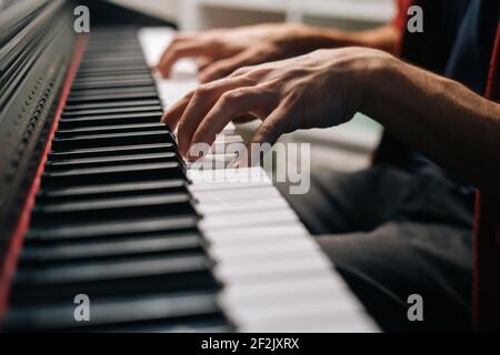 Close-up hands of unrecognizable musician man playing on synthesize at home studio during lesson. Stock Photo