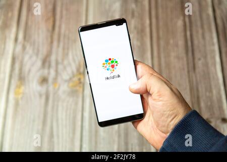 A Mobile phone or cell phone being held in a hand with the Hello talk app open on screen Stock Photo