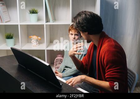 Caucasian boy playing synthesizer at home during lesson. Concept of music education. Stock Photo