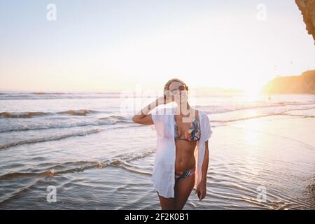 Woman in Tropical  Bikini on the Beach at Sunset Stock Photo