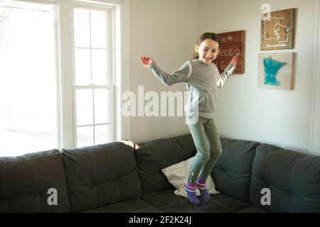 Little girl jumping on the couch. Stock Photo