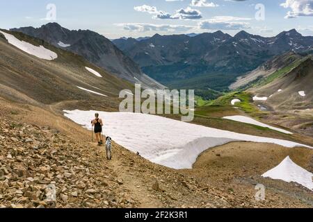 Rear view of woman hiking with dog on mountain in winter during vacation Stock Photo