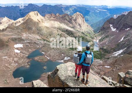 Rear view of couple looking at view while standing on mountain Stock Photo