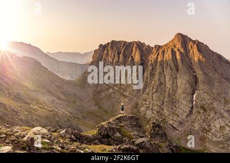 Woman looking at view while standing on peak of mountain against clear sky during sunset Stock Photo