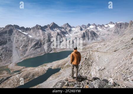 Rear view of man standing on mountain while hiking in vacation Stock Photo