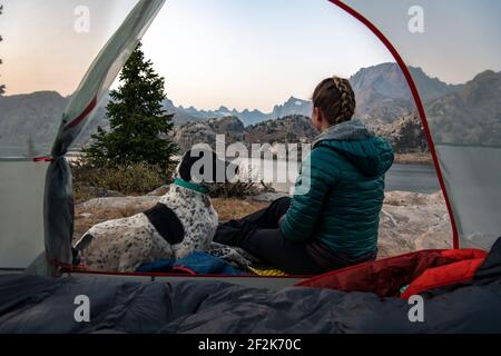 Woman sitting with dog by tent while camping during vacation Stock Photo