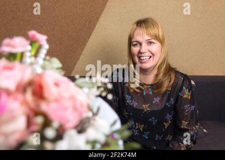 Smiling woman. Holiday. Beautiful middle-aged blonde woman feeling excited to receive lovely flower bouquet for spring holiday. Valentines day Stock Photo