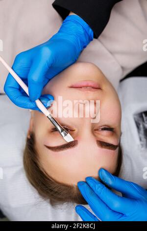 Woman with permanent makeup tattoo on her eyebrows. Close-up beautician makes a sketch of the eyebrows. Professional make-up and cosmetic skin care. Stock Photo