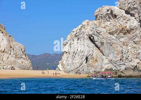 Tourist boat dropping tourists to sunbathe on secluded beach near the seaside resort Cabo San Lucas on the peninsula of Baja California Sur, Mexico Stock Photo