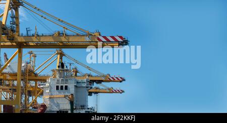 Worldwide shipping and cargo concept:  View on yellow crane lift standing at a dockyard to move containers. Construction equipment for logistics. Stock Photo