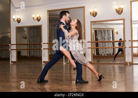 couple practicing to dance tango in a spacious empty hall, reflected in the mirror Stock Photo
