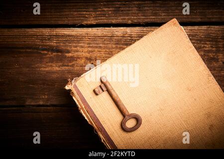 Old metal key on vintage book. Selective focus to key Stock Photo