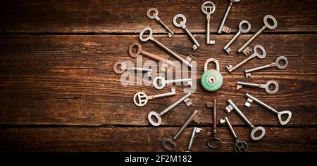 Vintage rusty padlock surrounded by group of old keys on a weathered wooden background. Internet security and data protection concept, blockchain and Stock Photo