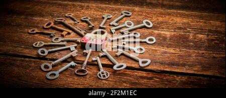 Vintage rusty padlock surrounded by group of old keys on a weathered wooden background. Internet security and data protection concept, blockchain and Stock Photo