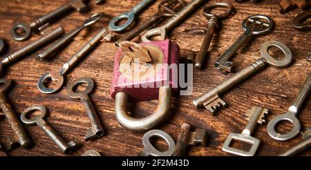 Vintage rusty padlock surrounded by group of old keys on a weathered wooden background. Internet security and data protection concept, blockchain and Stock Photo