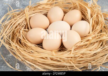 Bunch of raw eggs with bird nest on marble surface Stock Photo