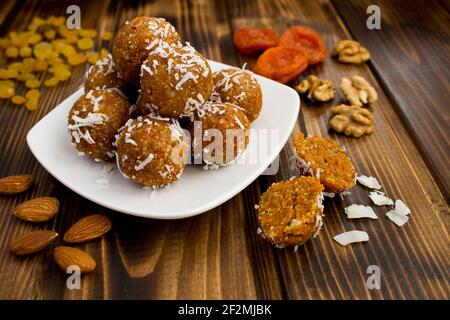 Energy balls with dried apricots and coconut chips in the white plate on the brown wooden background Stock Photo