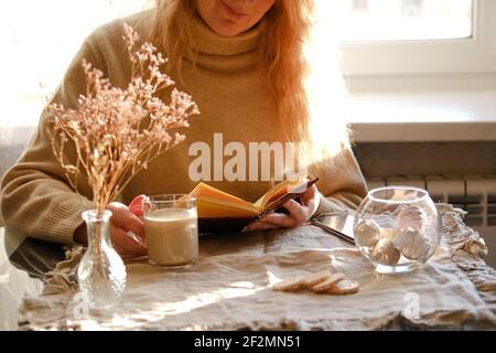 Cropped image of woman drinking coffee and reading a book Stock Photo