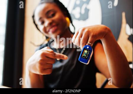 African american women with pulse oximeter on hand measuring oxygen saturation level. Stock Photo