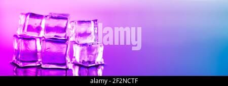 Ice cube. Close-up of melting ice cubes with pink and purple illumination on a black background. Macro horizontal photography. Stock Photo