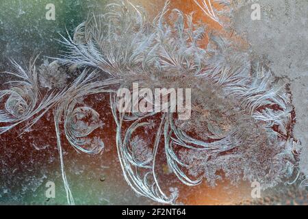 Jack Frost etchings on the window, with a colourful background. Stock Photo