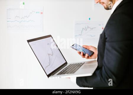 stock trader price trend graph analyzing on laptop and smartphone Stock Photo