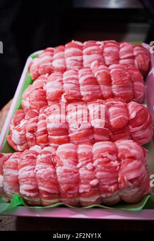 rolls of raw veal meat on a tray in an Italian butcher shop Stock Photo