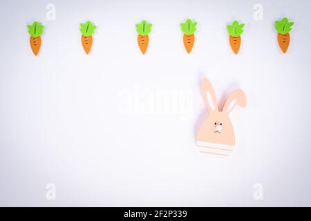 Easter pattern made with carrots and a cute Easter bunny on white background. Creative minimal holiday flat lay concept. Spring holidays concept. Stock Photo
