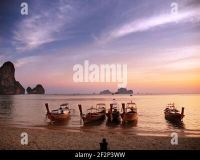 Longtail boats lie on the beach of Tonsai / Railay Beach and are illuminated by the setting sun Stock Photo
