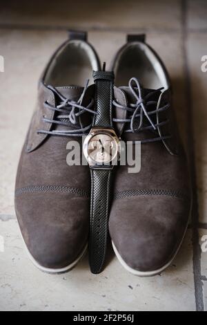 Mens brown shoes with laces and a wristwatch on the floor. Stock Photo