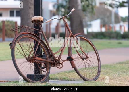 An old rusty bicycle leans up against a lamp post Stock Photo