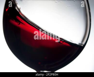 Red wine in wineglass on a grey background. Abstract splashing. Closeup. Stock Photo