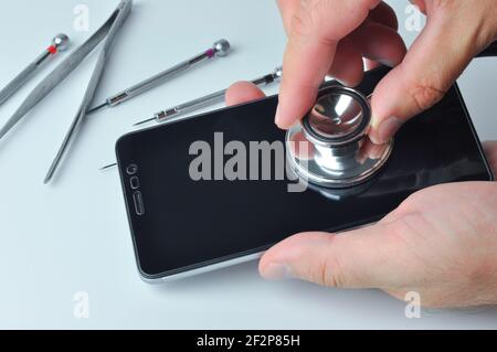 Men using a stethoscope for phone examination with empty copy space. Smartphone diagnostic, repair and service. Concept a repair devices. Stock Photo