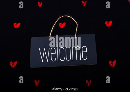 Welcome wording on black notice board  with red hearts around Stock Photo