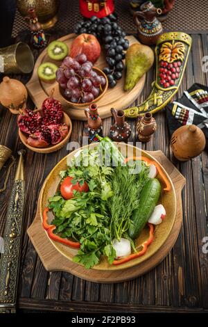 Bright fresh green salad leaves with red tomatoes, cucmbers and radish in the white bowl on wooden background Stock Photo