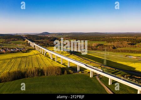 ICE, longest bridge in Thuringia (1681 m length, 48 m height), fields, flowering rapeseed, high voltage pylons, power line, aerial photo Stock Photo