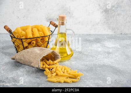 Penne pasta in a metallic container with olive oil on grey marble background Stock Photo