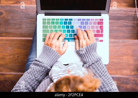Top view of female caucasian hands working on coloured keyboard of laptop computer - concept of connected people and smart worrking with home technology internet connection Stock Photo